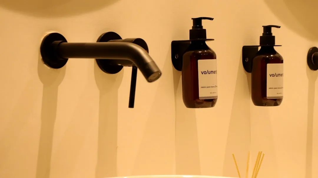 a bathroom sink with three soap dispensers on the wall