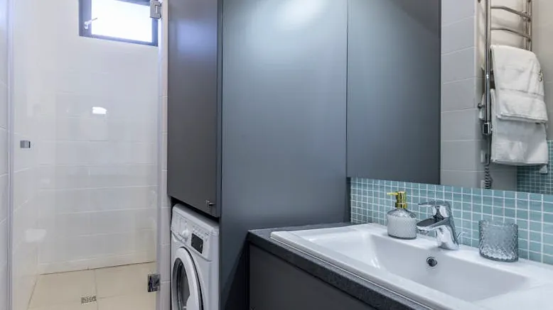 Contemporary bathroom in an apartment featuring a washing machine, shower, and sleek decor.