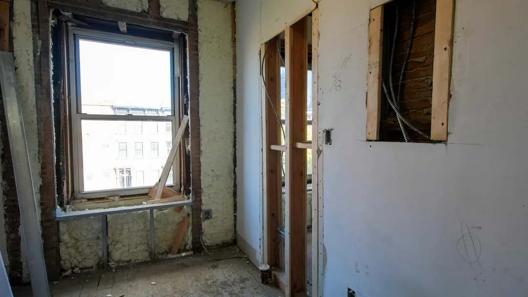 Interior room undergoing renovation with exposed walls and window.