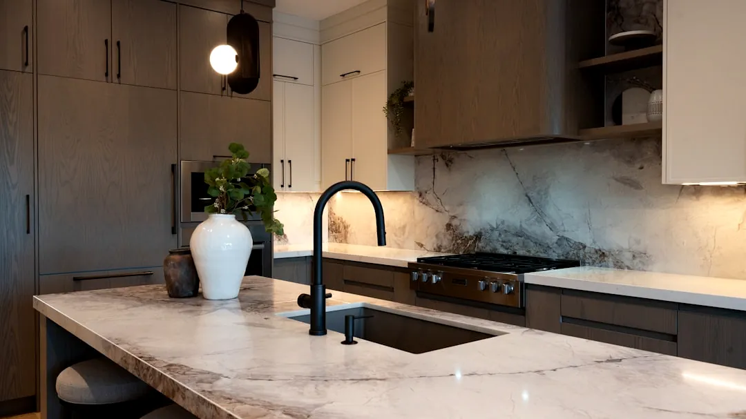 Modern kitchen with marble island and dark faucet.