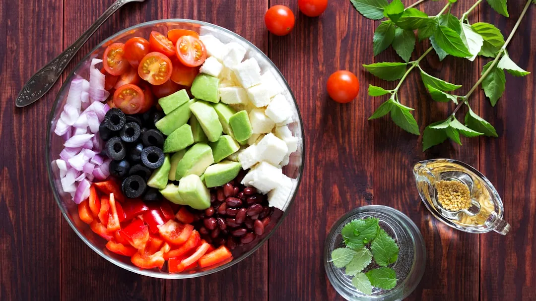 a bowl filled with vegetables and fruit on top of a wooden table