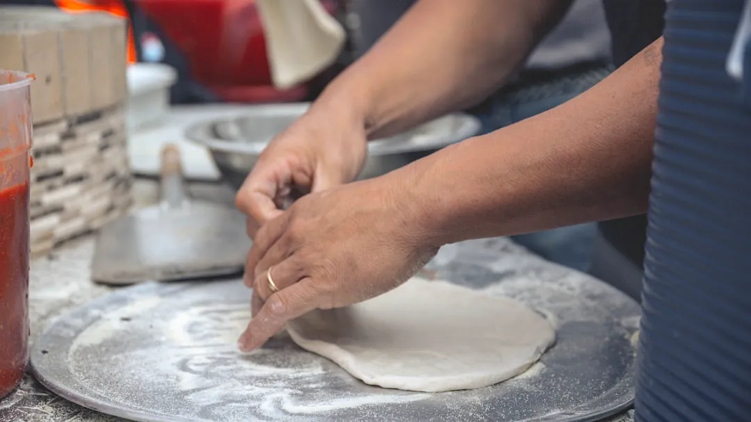 person holding white dough on white table