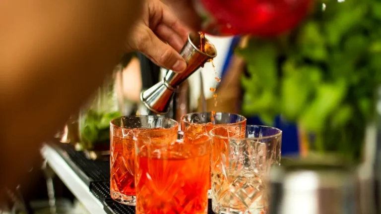 a person pouring a drink into glasses on a bar